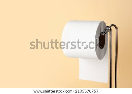Modern holder with toilet paper roll on beige background, closeup Royalty-Free Stock Photo #2105578757