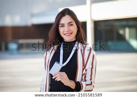Happy young woman holding an ID card on urban background Royalty-Free Stock Photo #2105581589
