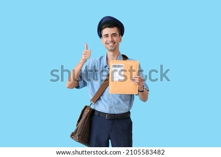 Handsome young postman with letter showing thumb-up on color background Royalty-Free Stock Photo #2105583482