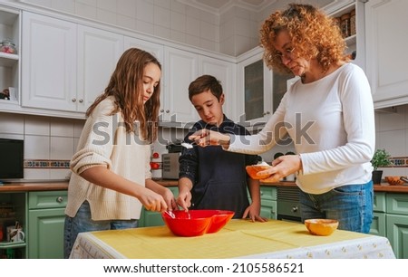 A mother and her children in the kitchen preparing a sponge cake