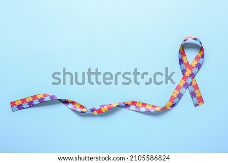 Awareness ribbon on blue background. Concept of autistic disorder Royalty-Free Stock Photo #2105586824