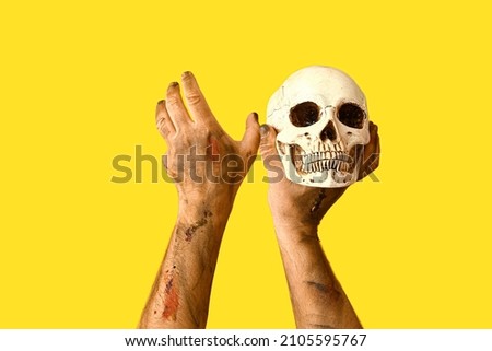 Hands of zombie with skull on color background