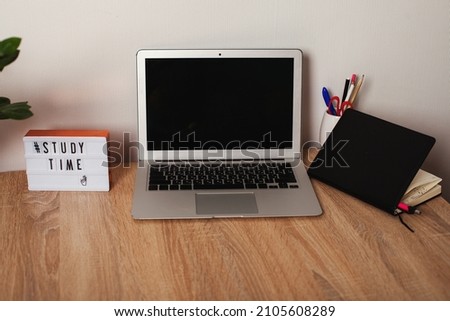 desktop with laptop, notepad and message on lightbox time to learn. study time