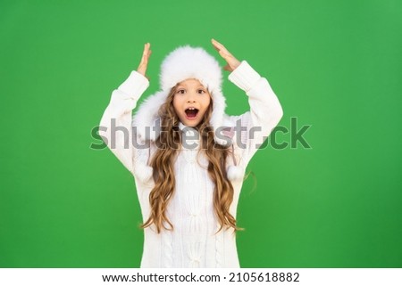 A girl in warm clothes points up at the advertisement.