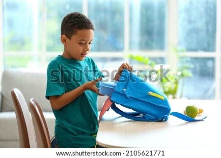 Cute little boy putting his school lunch in bag Royalty-Free Stock Photo #2105621771