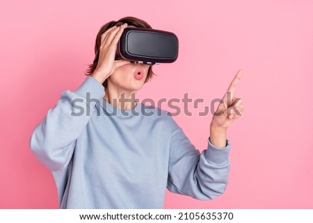 Portrait of attractive trendy amazed girl wearing digital helmet touching copy space isolated over pink pastel color background