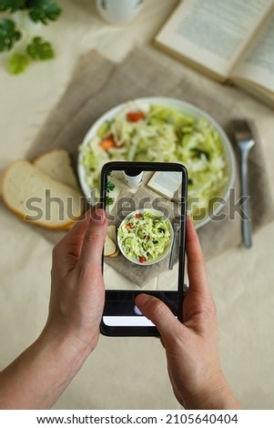 Woman hands take smartphone photo of food. Blogging and social media food photo on mobile camera. Phone fresh vegan salad with sesame seeds on plate photography. vertical