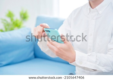 Asian man using the smartphone at home, no face