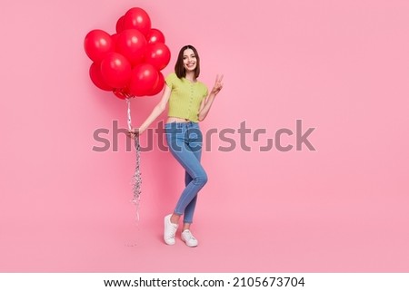 Full size photo of smiling pretty girl hold birthday balloons present show v-sign isolated on pink color background