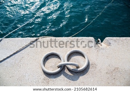 Iron rings on the pier where yachts are anchored in the marina. Two rings and ropes with which the boats are tied to the pier with ropes. The rings are in selective focus. Royalty-Free Stock Photo #2105682614