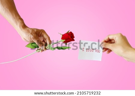 A man's hand sends a rose and a woman's hand sends a "I love you" message isolated on pink background with clipping path. valentine's day concept