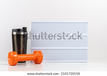 Fitness dumbbells with empty lightbox on white table. Mockup concept.
