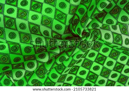 silk fabric of soft green color with a print of rhombuses, squares and medals. Tell a story and make a statement with traditional design work that has charm and value. Texture background pattern