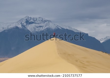 Traveler at the Chara sand dunes and overlooking the Kodar ridge Royalty-Free Stock Photo #2105737577