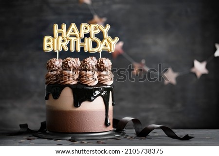 Chocolate birthday cake with  chocolate ganache drip icing and happy birthday banner Royalty-Free Stock Photo #2105738375