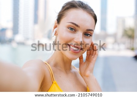 Young beautiful woman running otdoors and take a selfie picture on her smartphone