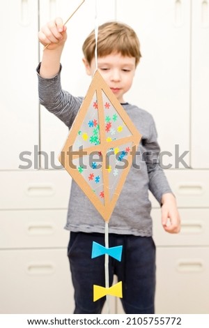 The child is creating a kite. The detail of the puzzle is a symbol of autism. Easy 5 minute crafts. Early preschool education for young children. Zero waste. DIY games at home.