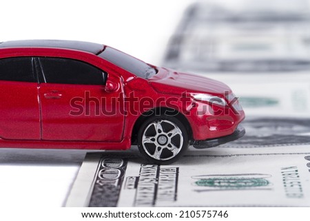 Small toy car on one hundred dollar banknotes as road, isolated on white background.