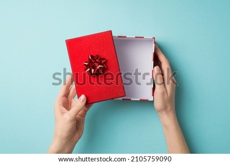 First person top view photo of valentine's day decorations woman's hands opening giftbox with red lid and star bow on isolated pastel blue background with empty space Royalty-Free Stock Photo #2105759090