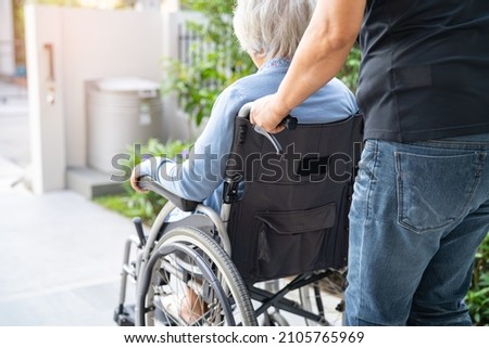 Caregiver help and care Asian senior or elderly old lady woman patient sitting on wheelchair at nursing hospital ward, healthy strong medical concept Royalty-Free Stock Photo #2105765969