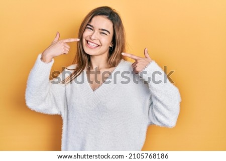 Young caucasian girl wearing casual clothes smiling cheerful showing and pointing with fingers teeth and mouth. dental health concept.  Royalty-Free Stock Photo #2105768186