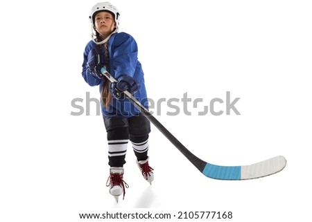 Maintaining sport spirit and physical strength. Full-length portrait of young girl hockey player in blue uniform with protective elements training on ice rink. Concept of competition, childhood, ad