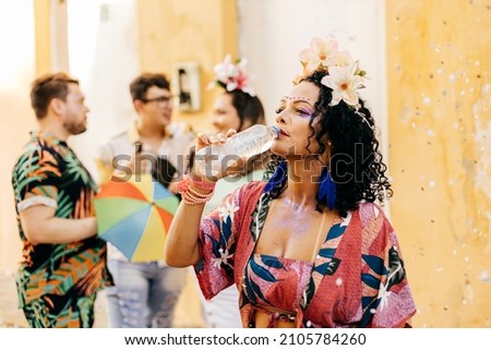 Brazilian Carnival. Woman drinking water during carnival block on the street Royalty-Free Stock Photo #2105784260
