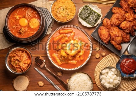 Traditional Korean food, Korean Fried chicken with spicy sauce  with rice, seaweed,fresh raw crabs marinated,spicy Rice Cake and Kimchi pickle on wooden table. Royalty-Free Stock Photo #2105787773