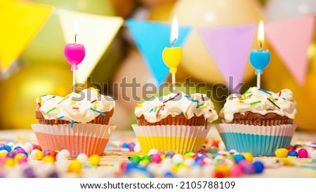 Multi-colored cupcakes with cream with a candle, happy birthday festive background