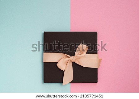 brown gift box with a cream bow on a pink and green background