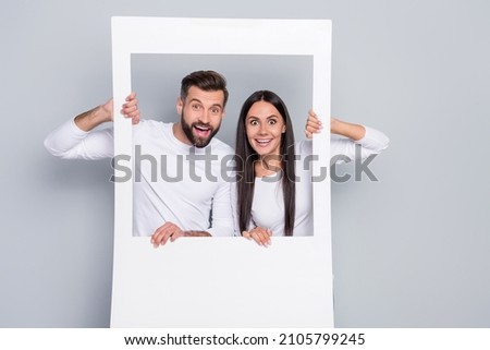 Portrait of attractive amazed cheerful couple having fun in photo frame border comfort zone isolated over grey pastel color background