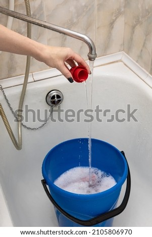 a woman's hand pours detergent from a cap into a bucket of water. High quality photo