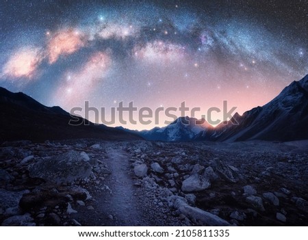 Arched Milky Way and mountains at night. Beautiful landscape with bright milky way arch, rocky path, starry sky at night in Nepal. Trail in mountain valley, sky with stars at sunrise. Himalayas. Space Royalty-Free Stock Photo #2105811335