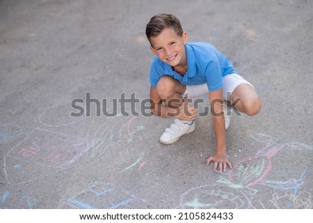 Happy boy approving his chalk drawings on the ground