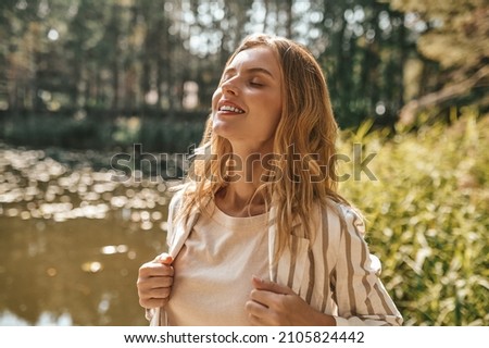 Beautiful relaxed long-haired woman on a river bank Royalty-Free Stock Photo #2105824442