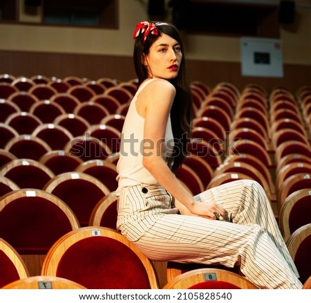 portrait of a pretty girl hipster in a movie theater wearing hat, dreaming alone, fashion lufestyle people concept