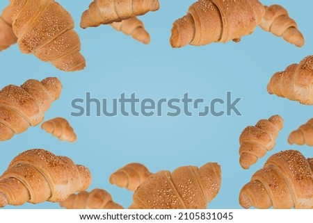 Frame of freshly baked croissants fly in the air isolated on a pastel blue background. Creative breakfast food concept. Copy space