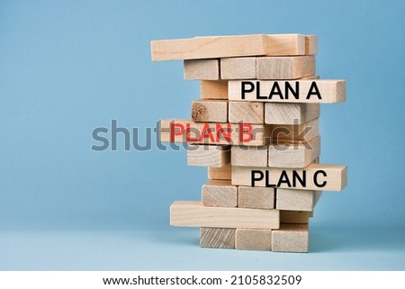Wooden blocks with words PLAN A, PlAN B, PLAN C on light blue background with copy space. Wooden tower. Business strategy, failure analysis and not give up. Business concept.