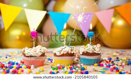Cream cupcakes with candle and sparkler, happy birthday festive background