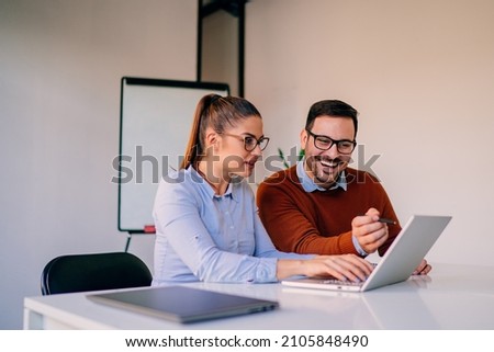 Happy businesspeople working together in the office while using laptop Royalty-Free Stock Photo #2105848490