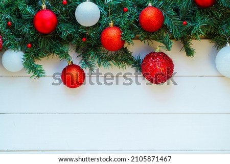 Christmas composition of fir tree branches, red and white baubles and holy berries on top border on white wooden background. Christmas, New year, holiday concept. Copy space, banner, flat lay.