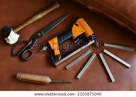 Upholstery tools on brown background, flat layer. Royalty-Free Stock Photo #2105875040