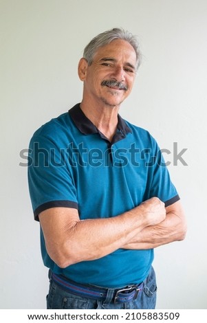 Retired man with arms crossed wearing blue shirts
