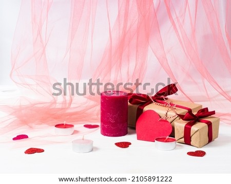 Pink candles, presents with red ribbons and hearts around on a white wooden table. Pink tulle on the background. Copy space. St. Valentines Day. Royalty-Free Stock Photo #2105891222