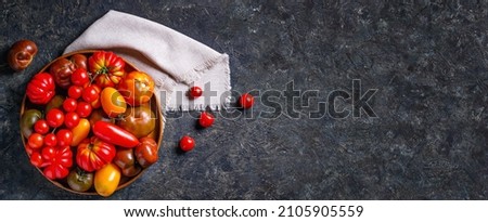 The harvest of assorted tomatoes, banner. Colorful organic tomatoes on a large dish. Tomatoes different varieties. Top view Royalty-Free Stock Photo #2105905559