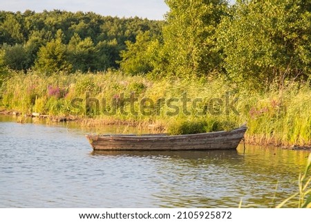 The view of a wooden boat at a lake at sunset light. Rural landscape.