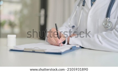 Close up of Doctor Writing Report on Paper