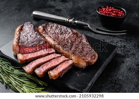Grilled top sirloin or cup rump beef meat steak on marble board. Black background. Top view Royalty-Free Stock Photo #2105932298