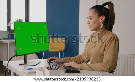 Person looking at green screen on computer display in office, working with isolated mock up template and chroma key on blank background. Business woman using mock-up on screen.