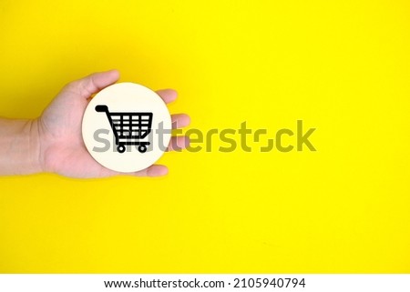 Top view hand hold of a shopping cart on a yellow background